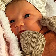 Lainey is registered to the contest to win money with this photo: newborn, baby, face, mittens, hat, blanket, close_up, portrait, soft_texture, warm_clothing, infant, sleepwear, cute, cozy, person, skin, headwear, resting, indoors, child