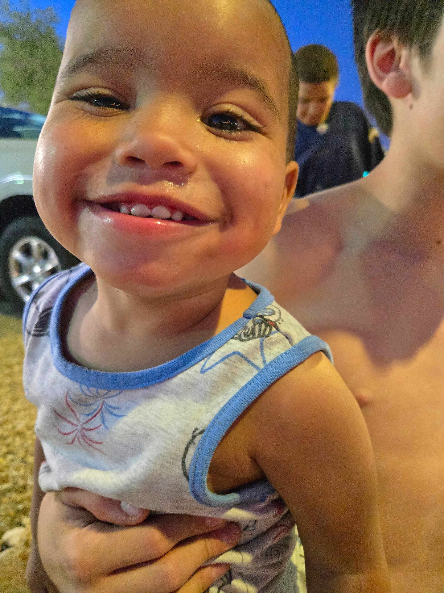 Hennessy joined the competition — help win amazing prizes! toddler, child, smile, happy, face, hand, shirtless, person, outdoor, evening, car, vehicle, tree, blue_sky, clothing, tank_top, closeup, portrait, cheeks, cute