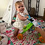 toddler, baby_walker, indoor, play_mat, teepee, toy, child, smiling, happy, floor, colorful, footwear_free, tattoo, adult_hand, cushion, carpet, furniture, window, person, room