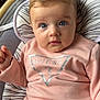 baby, blue_eyes, casual_wear, child, comfortable, cushion, cute, face, guess_logo, indoor, infant, long_sleeves, looking_at_camera, patterned_cushion, pink_clothing, portrait, seated, soft_hair, sweatshirt, young_child