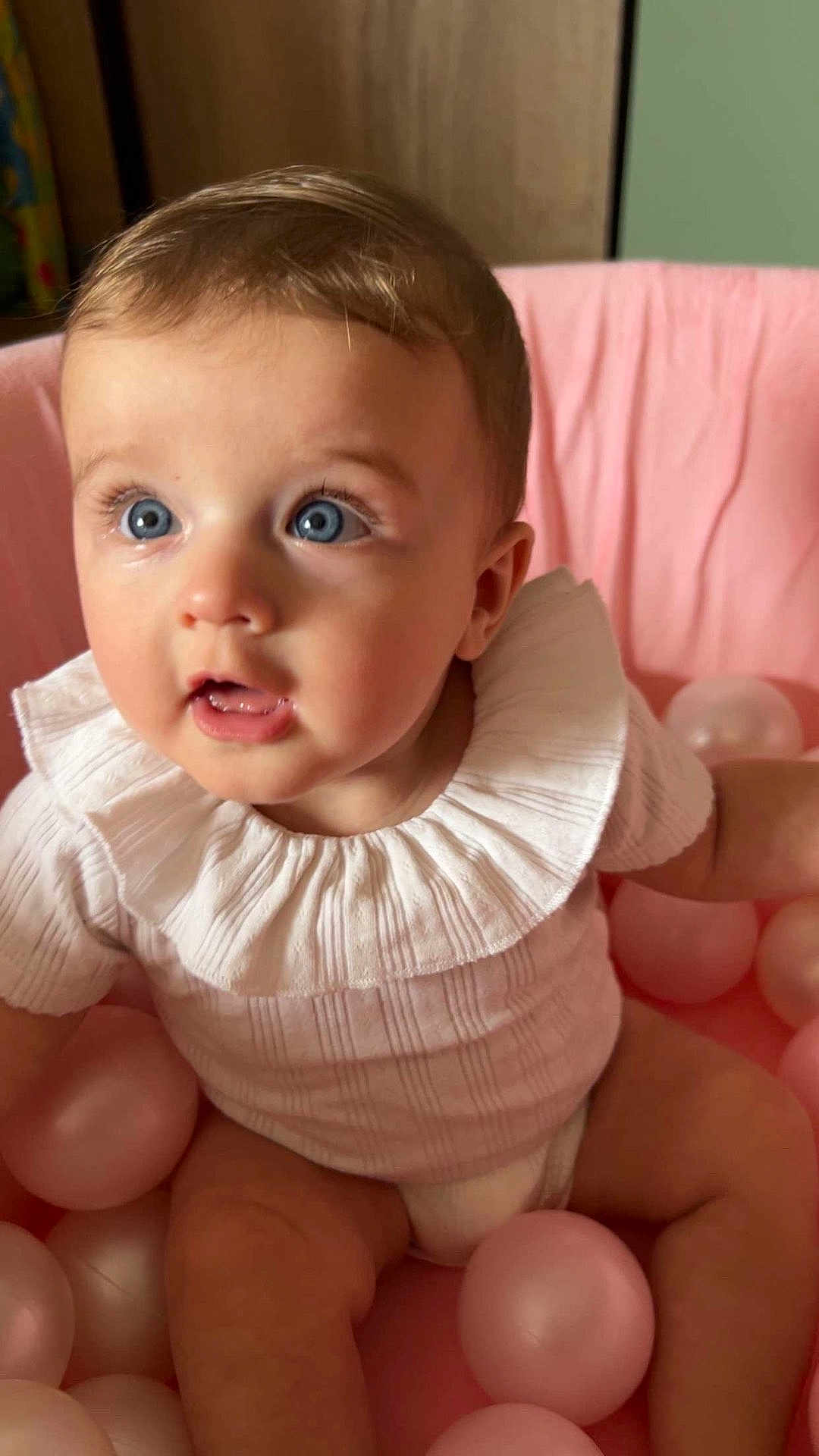 Abby participe au concours pour gagner de l'argent avec cette photo : baby, child, blue_eyes, pink, ball_pit, white_clothing, ruffled_collar, cute, infant, portrait, indoor, soft_lighting, curious, sitting, skin, face, head, person, early_childhood, toddler