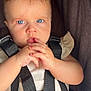 baby, blue_eyes, car_seat, child, close_up, curious_expression, face, hair, hands, indoor, infant, person, portrait, safety, seat, seatbelt, skin, straps, white_clothing, young_child