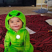 Davidson Flores joined the competition — help win amazing prizes! toddler, child, costume, green, smile, face, baby, sitting, blanket, pattern, indoor, carpet, toy, clothing, hood, pendant, furniture, home, baby_swing, cute