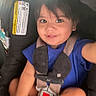 child, toddler, car_seat, blue_shirt, smile, baby, seatbelt, safety_harness, indoor, cute, happy, person, young_child, infant, car_interior, child_safety, sock, hair, face, portrait