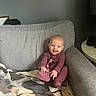 baby, blanket, casual, child, couch, cozy, cute, face, foot, furniture, hands, happy, home, indoors, infant, living_room, onesie, person, sitting, smiling