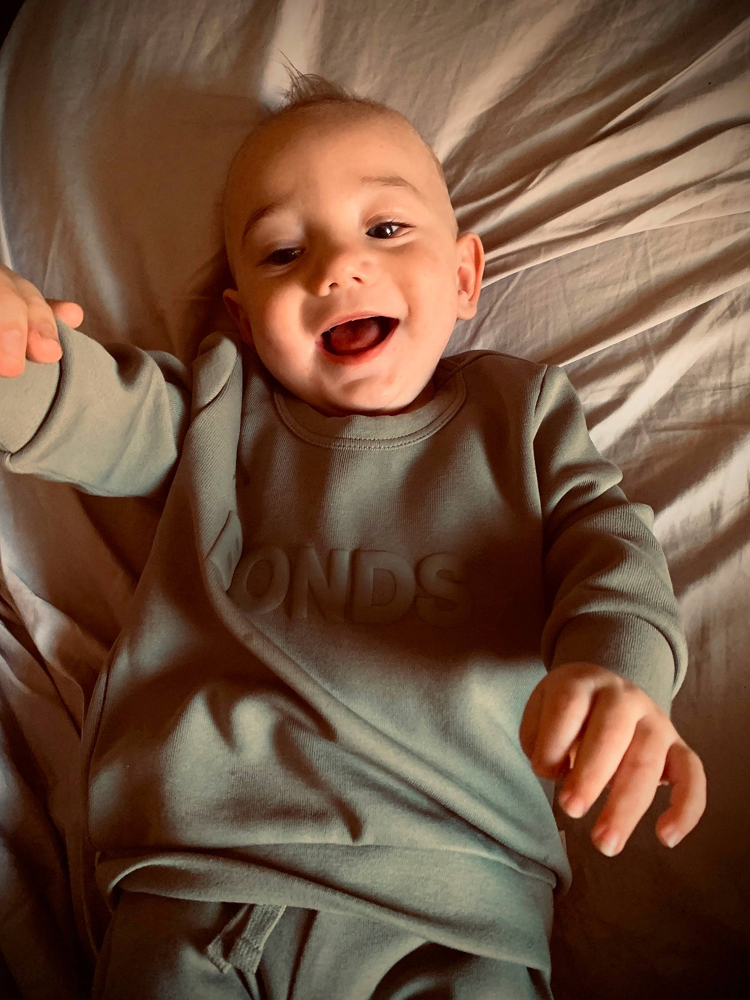 Arlo is registered to the contest to win money with this photo: arm, baby_toddler_clothing, cheek, chin, comfort, eye, eyebrow, facial_expression, hand, head, human_body, lip, mouth, neck, nose, organ, outerwear, person, skin, smile
