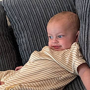 Isaac joined the competition — help win amazing prizes! baby, child, couch, striped_clothing, onesie, blue_eyes, hand, infant, portrait, indoor, cozy, fabric, texture, relaxed, cute, person, furniture, smile, young_child, curious