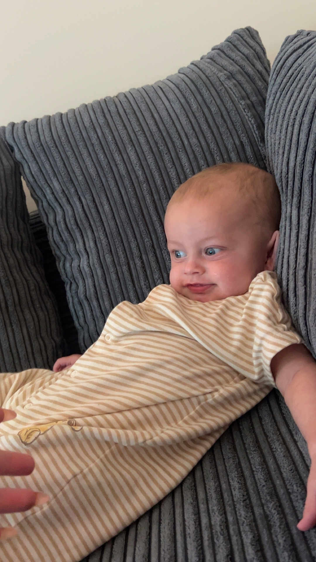 Isaac joined the competition — help win amazing prizes! baby, child, couch, striped_clothing, onesie, blue_eyes, hand, infant, portrait, indoor, cozy, fabric, texture, relaxed, cute, person, furniture, smile, young_child, curious