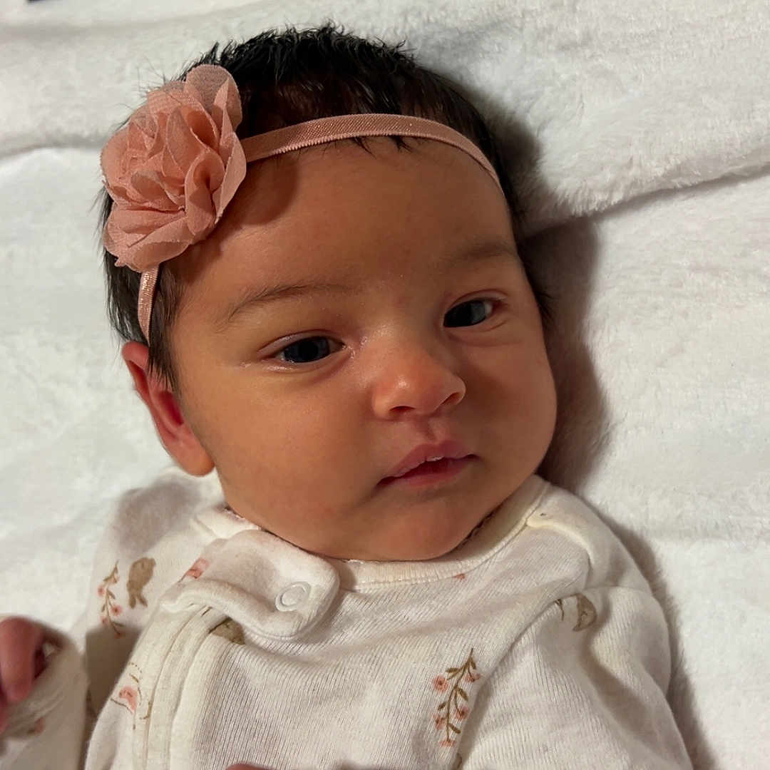 Kindsley is registered to the contest to win money with this photo: baby, blanket, closeup, cute, face, flower, hand, headband, indoors, infant, lying_down, newborn, pajamas, peaceful, portrait, skin, sleepy, soft_texture, white_clothing, young_child