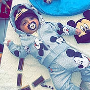 Emiliano a rejoint le concours — aidez-le/la à gagner de superbes lots ! baby, child, mickey_mouse, pacifier, hoodie, hat, blanket, toy, plush, shoes, floor, person, cute, clothing, indoor, accessories, pattern, lying_down, blue, gray