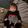 baby, child, pigtails, black_clothing, leopard_print, red_ribbon, sitting, bed, pillow, blanket, shoe, white_shoe, indoor, young_child, person, face, hair, cute, infant, portrait