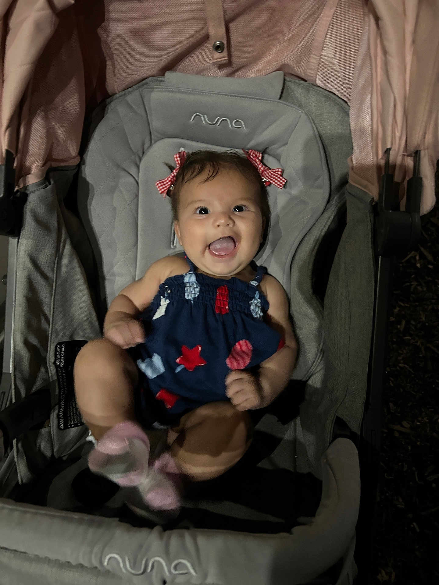 Isabella joined the competition — help win amazing prizes! baby, smiling, stroller, child, clothing, dress, hair_bows, pink_socks, happy, infant, seat, fabric, outdoor, night, person, cute, cheerful, playful, small_child, joy