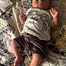 baby, infant, child, lying_down, quilt, bed, pacifier, diaper, clothing, shorts, shirt, patterned, indoor, cute, face, hands, feet, relaxed, young, resting