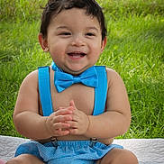 Daniel is registered to the contest to win money with this photo: baby, child, smiling, blue_bow_tie, blue_suspenders, outdoor, grass, quilt, happy, clapping, cute, infant, sitting, summer, portrait, cheerful, fun, toddler, bare_chest, sunlight