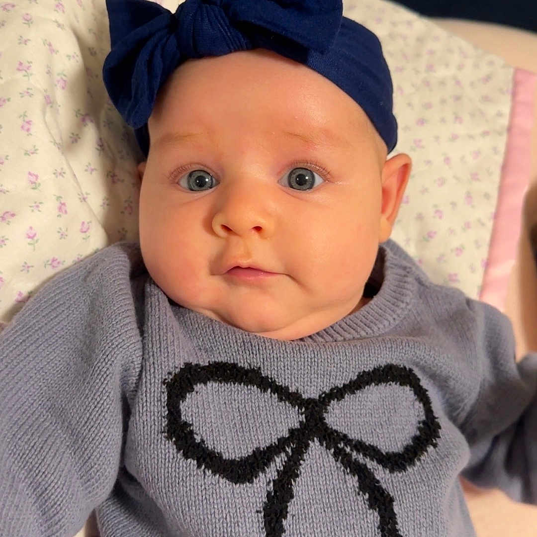 Kensington joined the competition — help win amazing prizes! baby, blanket, blue_eyes, bow, child, clothing, cozy, cute, expression, face, floral_pattern, headband, indoor, infant, newborn, person, portrait, soft_texture, sweater, warm