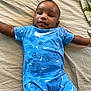 Idris is registered to the contest to win money with this photo: baby, infant, child, blue_onesie, sports_pattern, nike_logo, bed, blanket, smiling, arms_outstretched, cute, lying_down, face, head, skin, happy, indoor, portrait, clothing, person