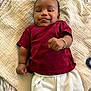 Idris joined the competition — help win amazing prizes! baby, infant, smiling, lying_down, blanket, maroon_shirt, white_pants, bracelet, cute, indoors, child, skin, hand, face, expression, happy, soft_texture, clothing, peaceful, portrait