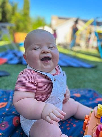 Reed is registered to the contest to win money with this photo: baby, blue, child, city, event, fun, grass, happy, laugh, leisure, people_in_nature, person, play, recreation, sitting, sky, smile, tableware, toddler, tree