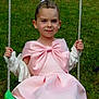 child, girl, swing, pink_dress, bow, grass, outdoor, play, ropes, smile, portrait, happy, summer, green, nature, fashion, childhood, leisure, fun, casual