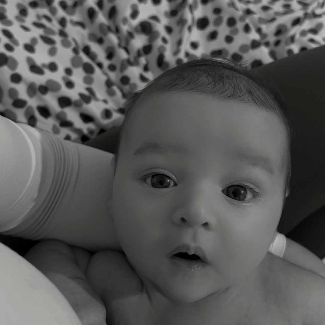 Filip is registered to the contest to win money with this photo: baby, black_and_white, blanket, closeup, clothing, comfort, cuddle, curious, expression, eyes, face, hand, infant, monochrome, newborn, pattern, person, portrait, skin, soft