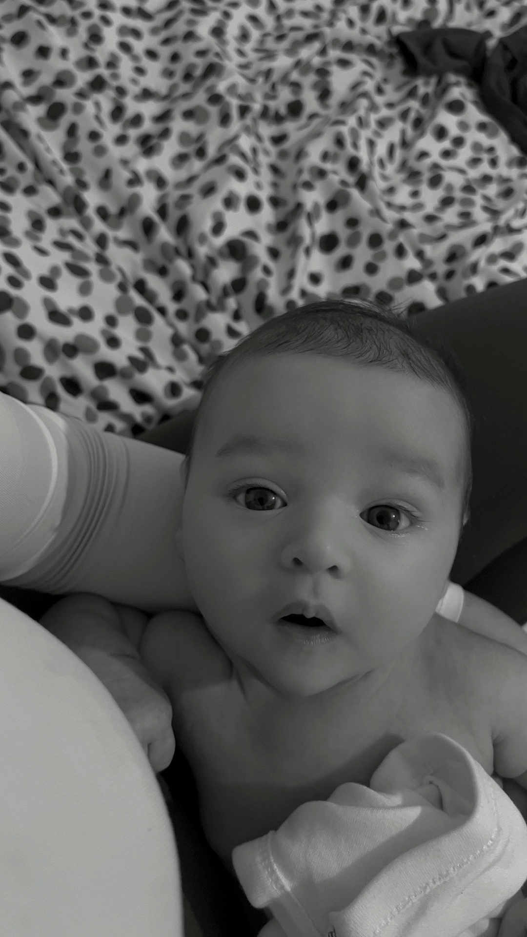 Filip is registered to the contest to win money with this photo: baby, infant, face, eyes, expression, blanket, pattern, soft, skin, person, newborn, curious, portrait, monochrome, black_and_white, clothing, hand, cuddle, comfort, closeup