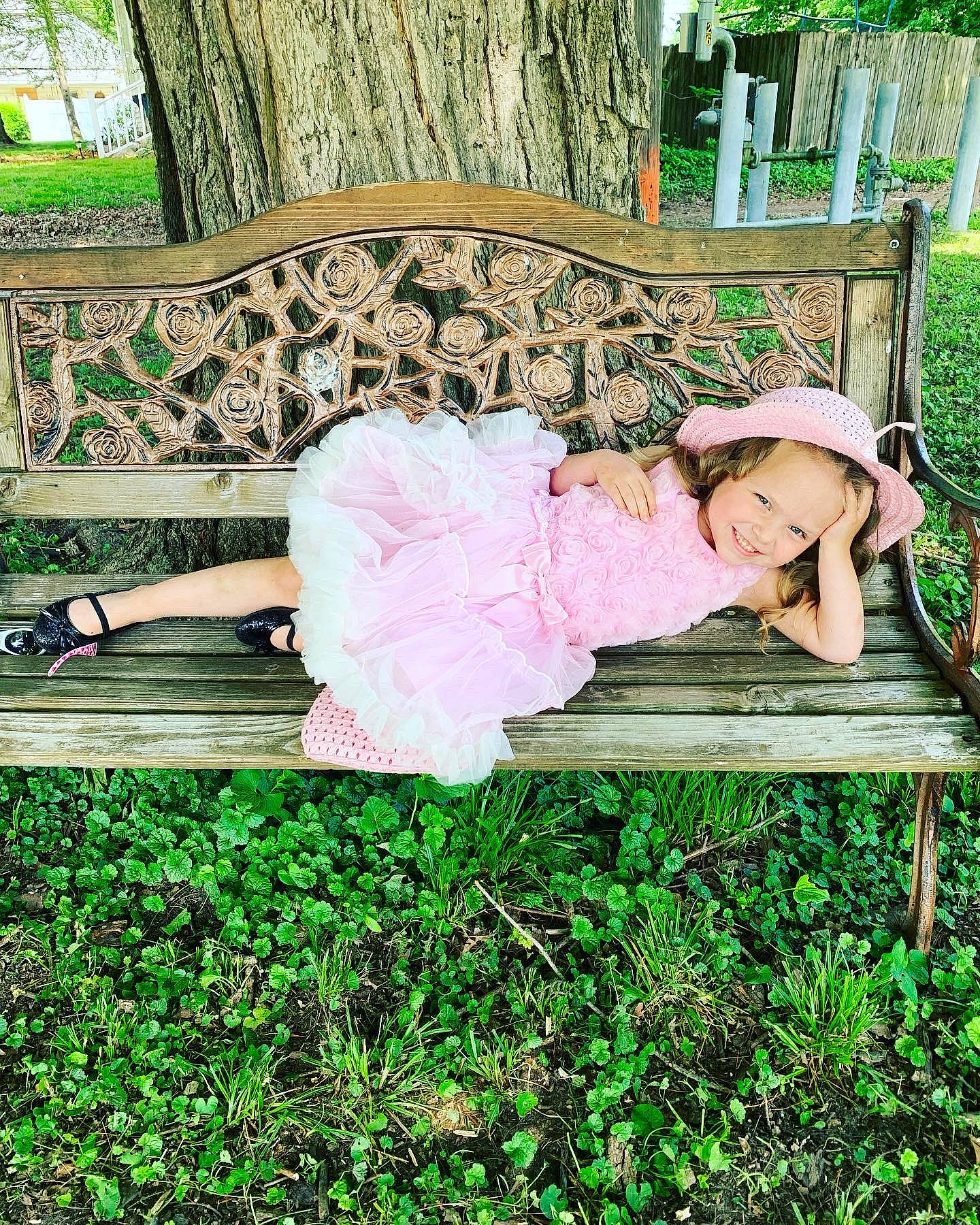Aubriella is registered to the contest to win money with this photo: baby_toddler_clothing, bench, child, dress, fun, grass, green, happy, hat, joy, leisure, magenta, outdoor_furniture, pattern, people_in_nature, person, plant, sitting, toddler, tree