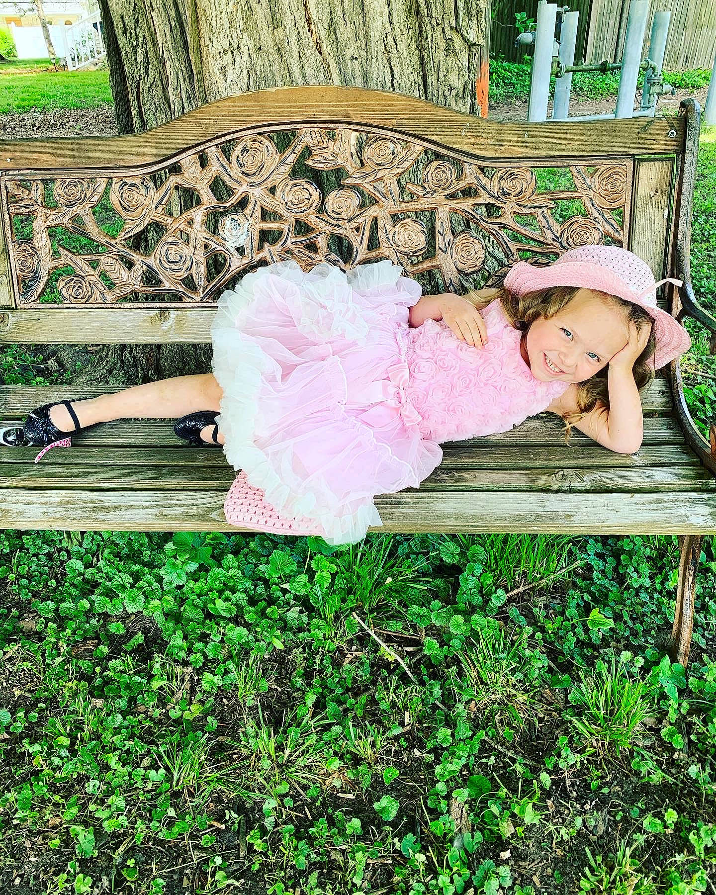 Aubriella is registered to the contest to win money with this photo: baby_toddler_clothing, bench, botany, child, garden, grass, green, hat, joy, leg, leisure, magenta, outdoor_furniture, pattern, people_in_nature, person, plant, shrub, sitting, sun_hat