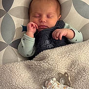Albane participe au concours pour gagner de l'argent avec cette photo : baby, newborn, sleeping_baby, blanket, pacifier, onesie, swaddle_blanket, hand, face, closed_eyes, bedding, nursery, patterned_pillow, cozy, infant_clothing, embroidered_text, small_hand, peaceful, soft_texture, sleeping