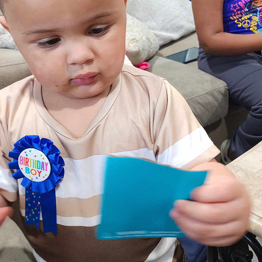 Byrson joined the competition — help win amazing prizes! badge, birthday, blue, card, child, clothing, curtains, cushion, floor, glasses, home, indoor, living_room, person, shorts, socks, sofa, table, toddler, window