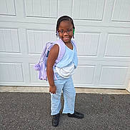 Saraya joined the competition — help win amazing prizes! backpack, beads, black_shoes, blue_outfit, braids, casual_clothing, child, confident, daylight, garage_door, girl, glasses, outdoor, pavement, person, portrait, ready_for_school, smiling, standing, young