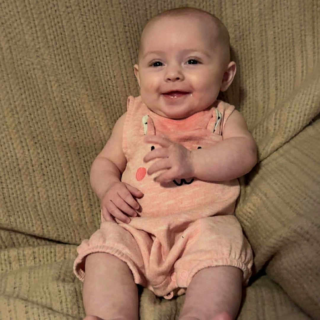 Lillianna is registered to the contest to win money with this photo: baby, infant, smile, onesie, peach, blanket, texture, sitting, happy, cute, portrait, child, fingers, feet, skin, head, face, indoor, comfort, cozy