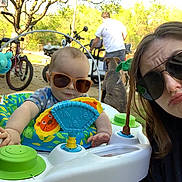 Ashton joined the competition — help win amazing prizes! baby, sunglasses, woman, man, dog, outdoor, toy, activity_center, bicycle, tree, person, playful, pout, face, sunlight, summer, greenery, casual, family, fun