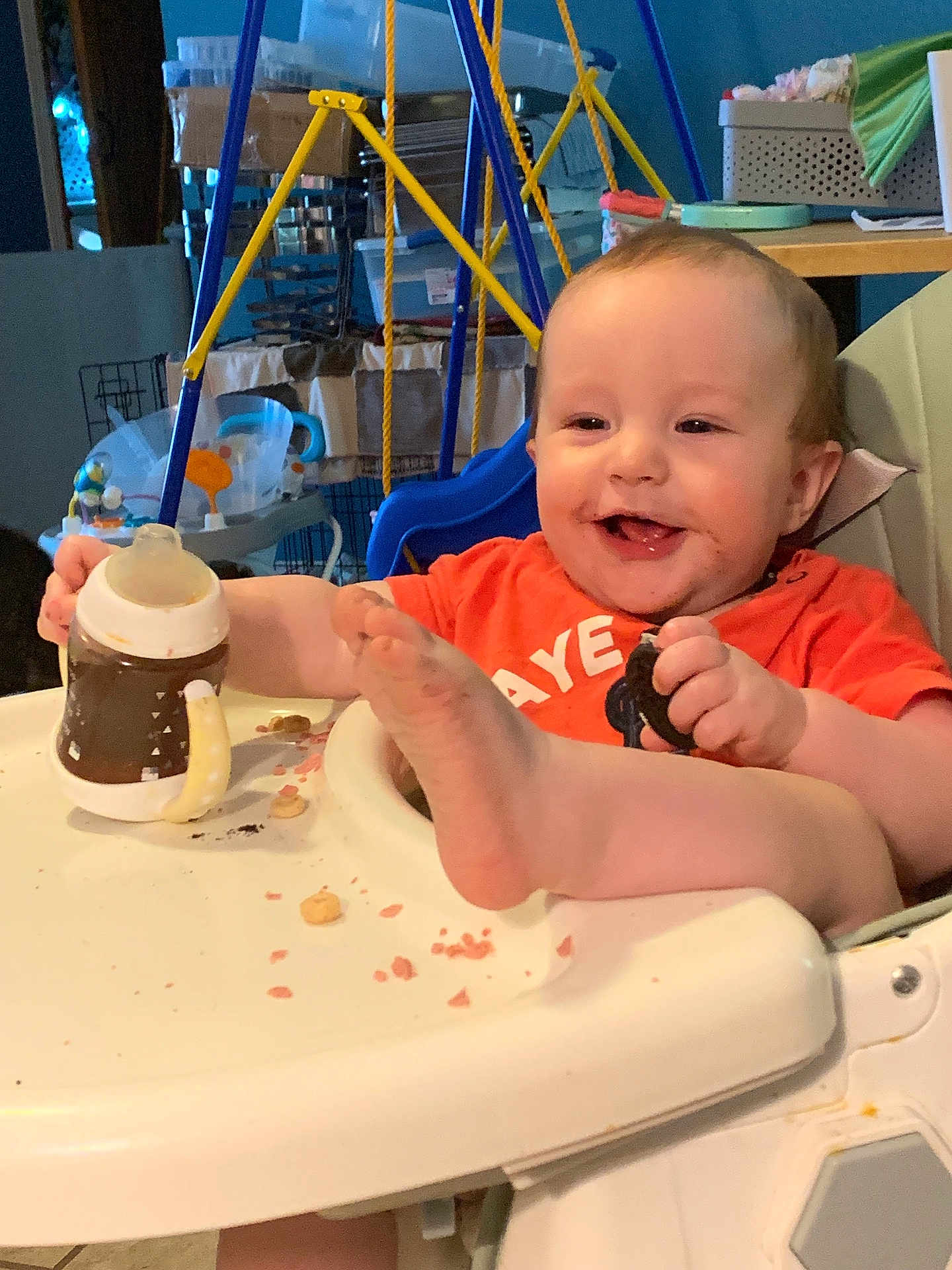 Ashton joined the competition — help win amazing prizes! baby, high_chair, food, crumbs, sippy_cup, cookie, smile, foot, indoor, toy, child, happy, playful, person, face, mouth_open, furniture, clothing, table, seat
