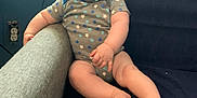 Ashton is registered to the contest to win money with this photo: baby, smiling, onesie, couch, blue, armrest, home, infant, happy, face, legs, feet, wall, socket, plush, child, person, indoors, relaxed, seated