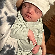 Josiah is registered to the contest to win money with this photo: newborn, baby, sleeping, hat, infant, person, hand, clothing, soft, cozy, indoor, closeup, cradled, peaceful, skin, apparel, resting, human, headwear, toddler