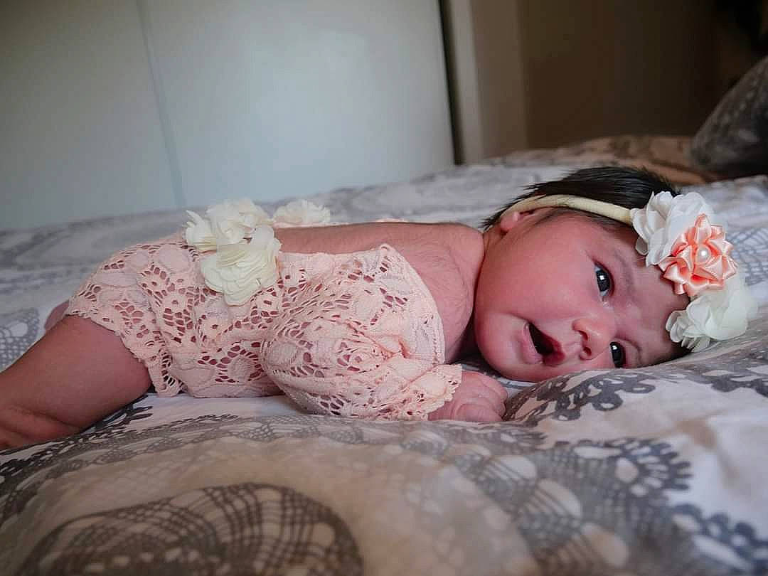 Avelyne a rejoint le concours — aidez-le/la à gagner de superbes lots ! baby, baby_toddler_clothing, bedding, blond, brown_hair, child, comfort, couch, eye, flash_photography, headwear, iris, linens, lip, pattern, person, pink, sitting, skin, sleeve