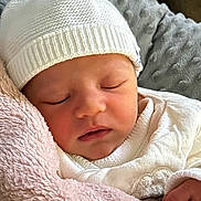 Mia a rejoint le concours — aidez-le/la à gagner de superbes lots ! newborn, baby, sleeping, white_hat, white_clothing, blanket, plush_blanket, soft_texture, close_up, face, infant, peaceful, cozy, resting, indoors, portrait, child, cute, warm, toddler