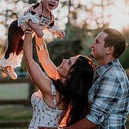 Ivory Grace is registered to the contest to win money with this photo: baby, child, woman, man, family, outdoor, sunlight, smile, happy, playing, dress, plaid_shirt, bracelet, necklace, nature, fence, grass, portrait, love, joy