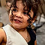 black_clothing, buttoned_clothing, child, closeup, curly_hair, cute, earrings, face, fashion, hair, happy, indoor, jewelry, person, portrait, skin, smiling, vest, white_clothing, young_child