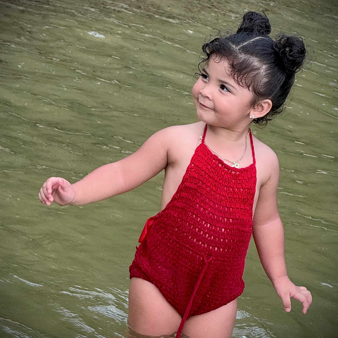 Valentina is registered to the contest to win money with this photo: arm, child, cute, hair_buns, happy, nature, outdoor, person, playful, portrait, red_clothing, skin, smile, standing, summer, swimsuit, toddler, water, water_body, young_child