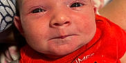 Gracelynn Ann Marie is registered to the contest to win money with this photo: baby, infant, child, face, smile, red_shirt, text_on_clothing, cute, closeup, skin, expression, person, newborn, indoors, fabric, clothing, head, eyes, cheeks, human