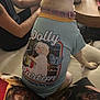 dog, shirt, dolly_parton, couch, person, tattoo, pillow, living_room, collar, table, indoor, pet, sitting, animal, clothing, human_arm, furniture, relaxing, casual, cute