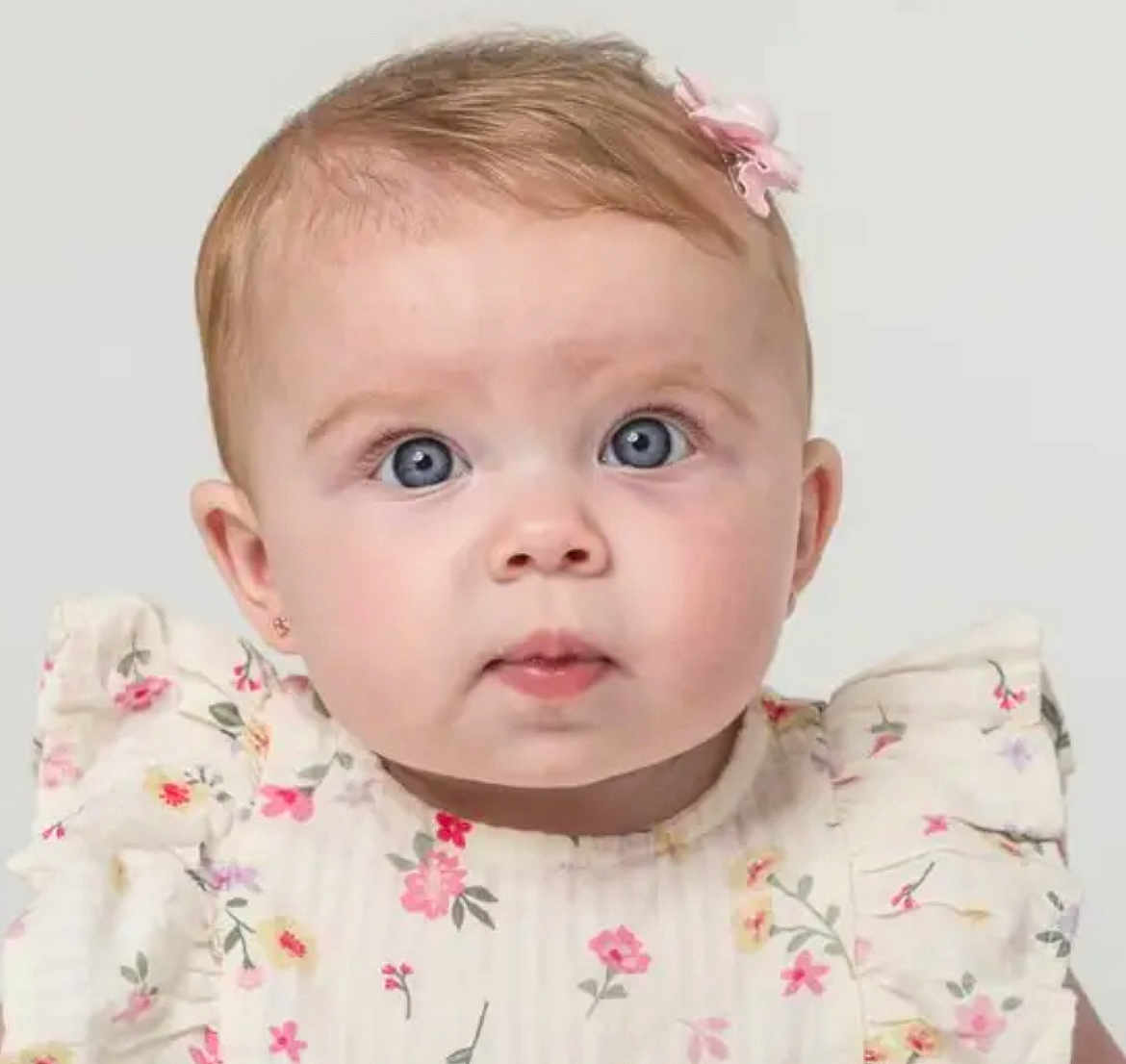 Isla-May joined the competition — help win amazing prizes! baby, child, portrait, close_up, blue_eyes, flower_pattern, dress, ruffles, pink_bow, curious_expression, infant, cute, young_child, headshot, studio_photo, light_background, soft_lighting, face, small_ears, innocent