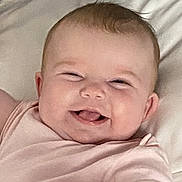 Isla-May is registered to the contest to win money with this photo: baby, smiling, infant, pink_clothing, happy, cute, face, lying_down, hand, skin, bed, pillow, blanket, child, person, young_child, indoors, portrait, closeup, joyful