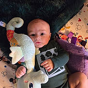 Carter joined the competition — help win amazing prizes! baby, infant, stuffed_toy, plush, playmat, blanket, child, person, face, hand, legs, clothing, green_outfit, toy, indoor, colorful, patterned, cute, lying_down, soft