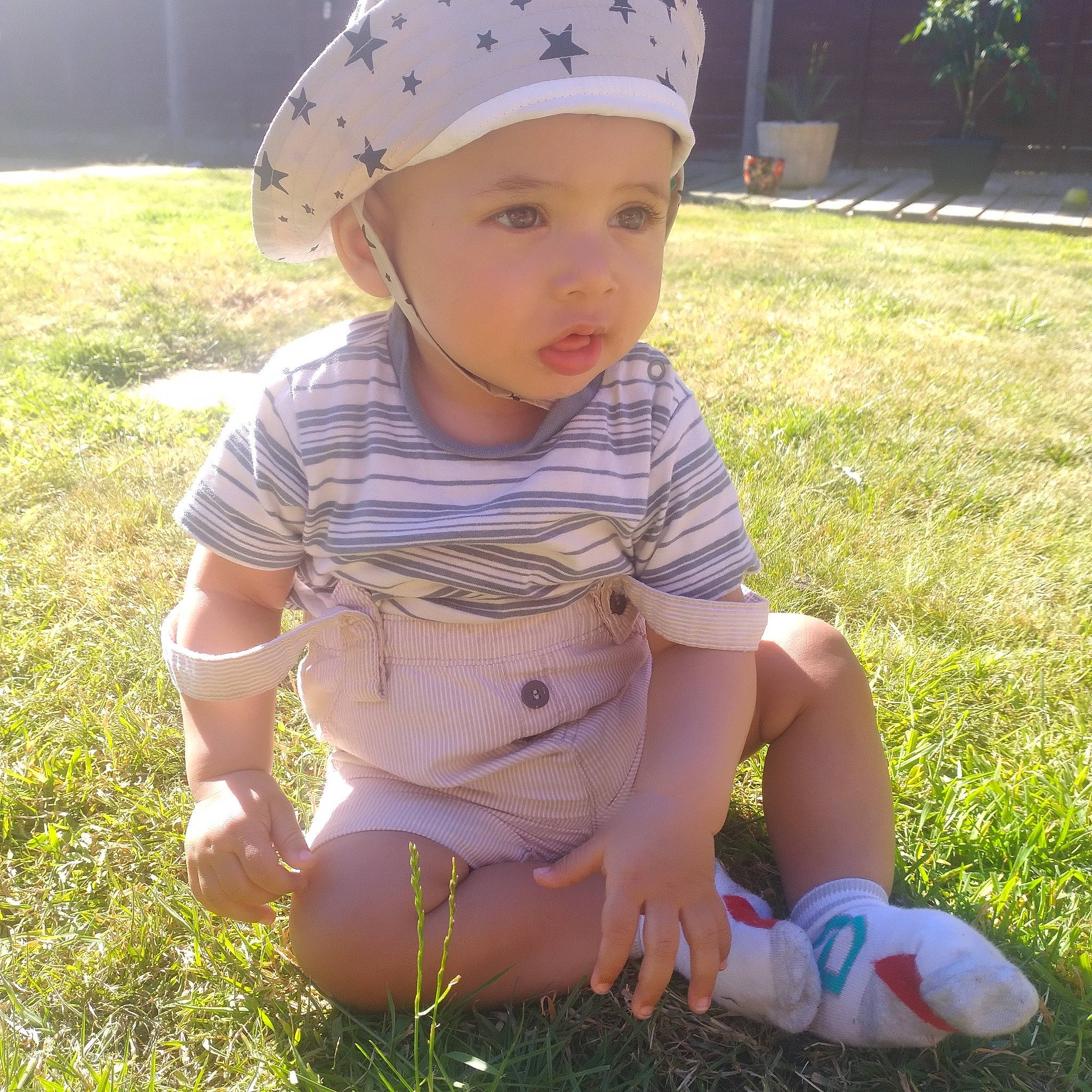 Elias is registered to the contest to win money with this photo: baby_toddler_clothing, cap, child, fashion_accessory, foot, fun, grass, happy, headwear, human_leg, lawn, light, people_in_nature, person, personal_protective_equipment, pink, plant, spring, summer, thigh