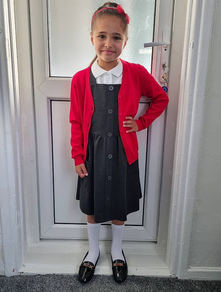 Anayah is registered to the contest to win money with this photo: baby_toddler_clothing, blazer, child, clothing, collar, door, electric_blue, fashion_design, formal_wear, hat, joy, knee, outerwear, pattern, person, school_uniform, sleeve, smile, sock, standing