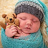 newborn, baby, sleeping, knitted_hat, teddy_bear, blanket, wrapped, soft_background, closeup, infant, cute, peaceful, portrait, child, tiny_hands, cozy, warm, fabric, plush, resting