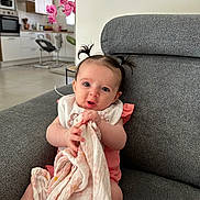élya a rejoint le concours — aidez-le/la à gagner de superbes lots ! baby, infant, child, blanket, armchair, pigtails, pink, white, gray, clothing, face, person, indoor, kitchen, furniture, curious, expression, holding, cute, home