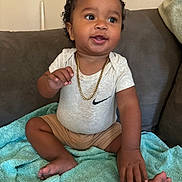 Kay Veon Boren joined the competition — help win amazing prizes! baby, barefoot, blanket, brown_skin, child, closeup, couch, curly_hair, happy, home, indoor, infant, looking_away, necklace, nike_logo, portrait, shorts, sitting, smiling, white_shirt